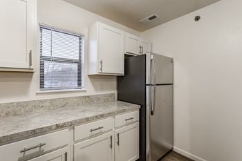 A kitchen with a black refrigerator and white cabinets